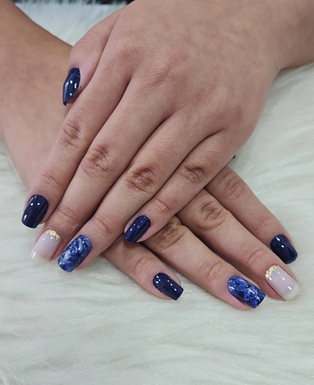 Nail art azul marinho com detalhes brancos e dourados